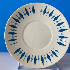 Puede incluir: Plato blanco con un patrón geométrico azul y blanco. El patrón presenta diamantes y estrellas.