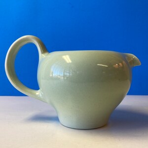 May include: A light green ceramic creamer with a rounded body and a curved handle.