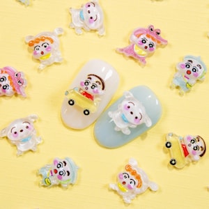 May include: A collection of colorful nail art decorations featuring cartoon characters and animals. The decorations include figures of a boy in a car, a dog, and other characters in various poses. The background is a light yellow color.