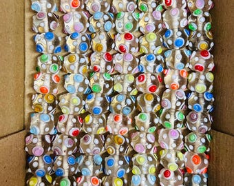 May include: A collection of clear glass beads with colorful polka dots in a cardboard box. The beads have a variety of colors, including red, yellow, blue, green, and pink. Each bead is approximately 0.5 inches in diameter.