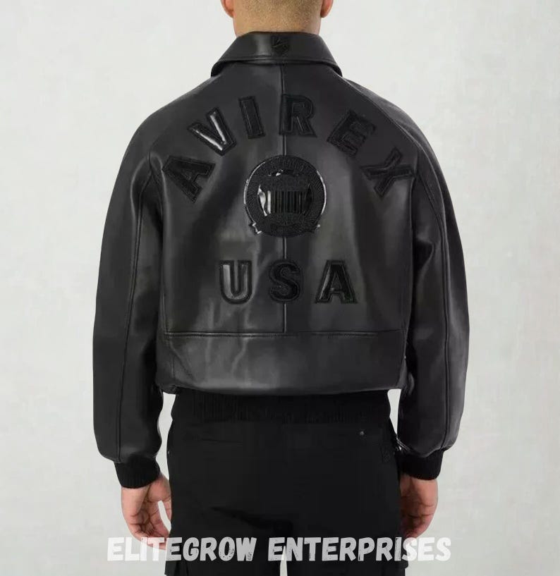 Puede incluir: Chaqueta bomber de cuero negro con la palabra "AVIREX" arqueada en la espalda, encima de un emblema circular y la palabra "USA". La chaqueta tiene dobladillo y pu&ntilde;os de canal&eacute;. Un estilo cl&aacute;sico.