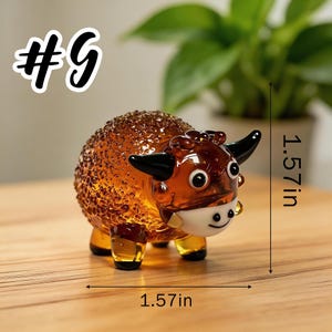 May include: A glass figurine of a bull, 1.57 inches in length and height. The bull is brown with black horns and a white face. The figurine has a textured body and is labeled with the number 9.
