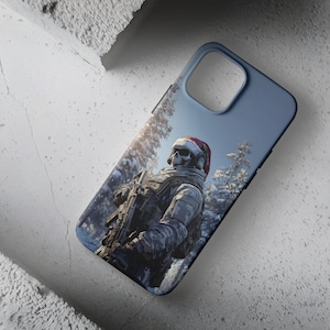 May include: A blue phone case depicting a soldier with a skull mask and a Santa hat in a snowy forest. The soldier is armed with a rifle. The case has a matte finish and is designed for a smartphone.