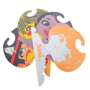 Op de afbeelding: Een verzameling kleurrijke, gestanste gezichtsvormige decoraties. De gezichten hebben verschillende huidtinten, haarkleuren en gezichtsuitdrukkingen. Eén wit gezicht heeft de naam "Susi" erop gedrukt. De decoraties zijn gemaakt van karton en hebben een gat aan de bovenkant.