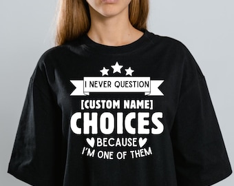 May include: Black t-shirt with white text. The text reads "I NEVER QUESTION [CUSTOM NAME] CHOICES BECAUSE I'M ONE OF THEM" with three stars above the text. The shirt is a crew neck.