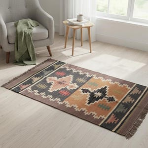 Può includere: Tappeto rettangolare con un motivo geometrico nei toni del marrone, nero, arancione e verde. Il tappeto ha un bordo con frange ed è posato su un pavimento in legno chiaro. Un elemento decorativo per un soggiorno, misura circa 150 cm x 90 cm.