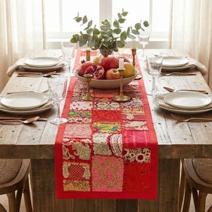 Könnte beinhalten: Ein rustikaler Holztisch, gedeckt für ein Essen. Der Tisch ist mit weißen Tellern, Besteck und einem roten Patchwork-Läufer geschmückt. Eine Schale mit Obst und Grünzeug sorgt für eine dekorative Note.