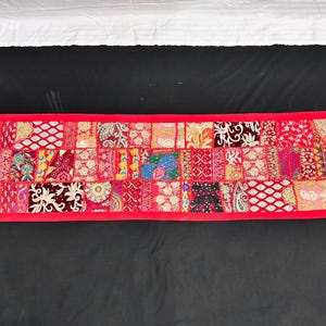 May include: A rectangular, patchwork textile with a vibrant red border. The interior is composed of numerous squares, each featuring a unique pattern in shades of red, pink, and gold. The textile is likely a decorative item, such as a table runner or wall hanging.