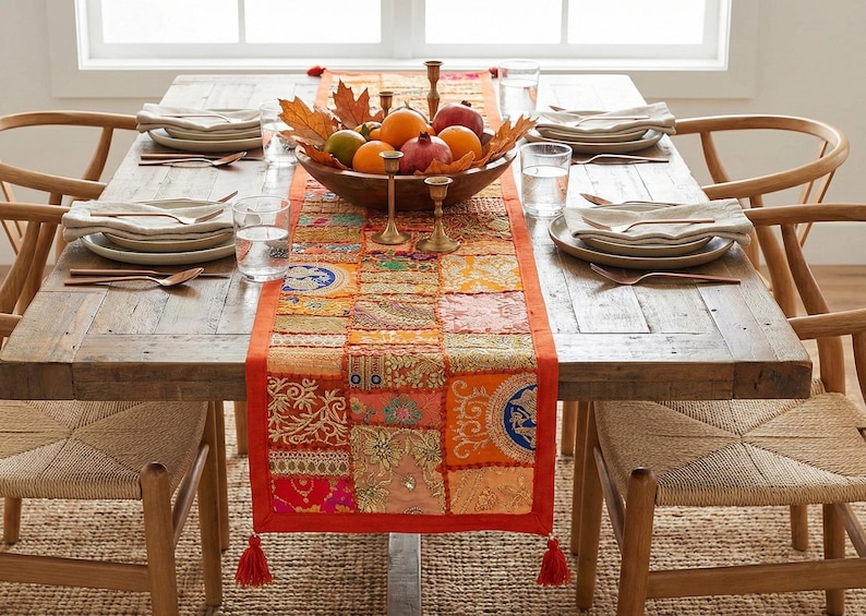 May include: A rustic wooden dining table set for a meal. The table is adorned with a colorful patchwork runner, a wooden bowl of fruit, and brass candle holders. Each place setting includes plates, silverware, and a glass of water. Woven chairs surround the table.