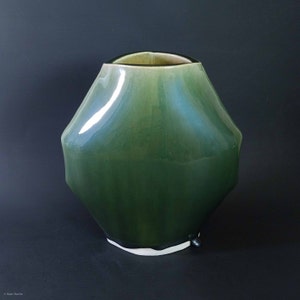 Peut inclure: Un vase en céramique vert avec une forme arrondie et organique. Le vase a une finition brillante et un effet ombré subtil, passant d'un vert plus clair en haut à un vert plus foncé en bas.