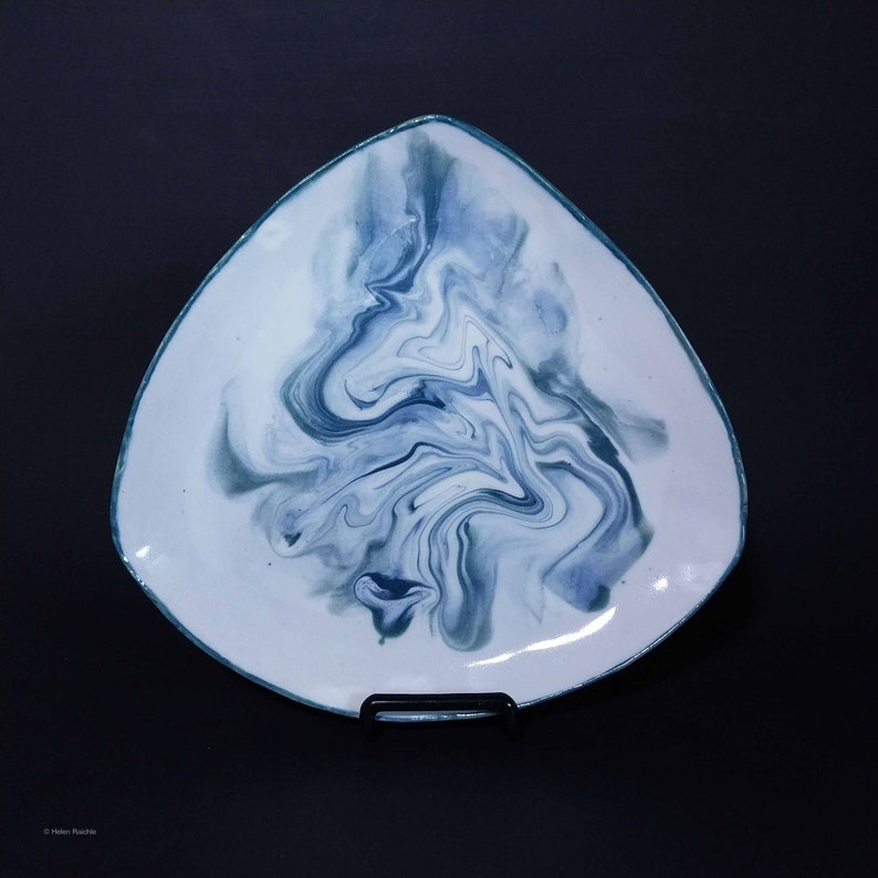 K&ouml;nnte beinhalten: Eine dreieckige Keramik-Servierplatte mit wei&szlig;er Glasur und einem blauen und gr&uuml;nen Marmormuster.