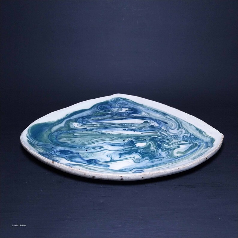 K&ouml;nnte beinhalten: Ein quadratischer Keramikteller mit wei&szlig;em Hintergrund und einem blauen und gr&uuml;nen Marmormuster.