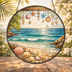 Puede incluir: Vidriera redonda que representa una escena de playa con un velero en el mar. La obra de arte presenta conchas marinas, estrellas de mar y una hoja de palma. La ventana está enmarcada en metal oscuro y cuelga de una cadena.