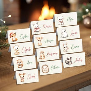 Peut inclure: Ensemble de cartons de table pliés avec des illustrations à l'aquarelle d'animaux de la forêt, chacun portant un nom en écriture élégante. Les cartes présentent un renard, un ours, un cerf et d'autres animaux, parfaites pour une fête.