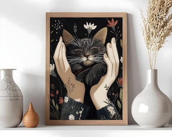 Puede incluir: Una impresión artística enmarcada que muestra un gato abrazado por manos, sobre un fondo negro con flores. El gato tiene los ojos cerrados. Hay jarrones decorativos en el estante.