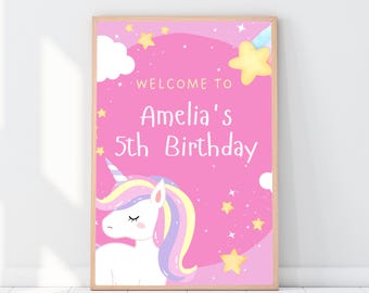 May include: A framed pink birthday sign with a unicorn illustration. The sign reads "Welcome to Amelia's 5th Birthday" in white text. The unicorn has a colorful mane and horn, with yellow stars and clouds scattered around the design.