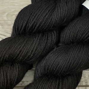 May include: Two skeins of black yarn with the label "JUICY WOOLS" on each skein.