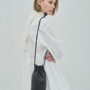 Bolso de hombro minimalista negro con borlas y cordón de piel de cabra