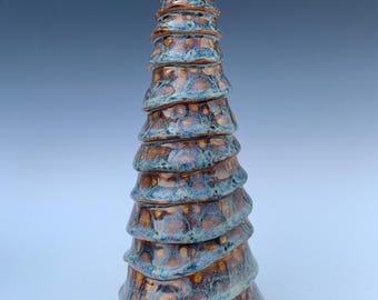 May include: A ceramic sculpture in a spiral form, with a layered design and textured surface. The piece has brown and blue-green tones, creating a unique decorative item. The height is approximately 25 cm.