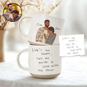 Puede incluir: Dos tazas de cerámica blanca con diseño moteado y base beige. Una taza presenta un retrato de pareja y nombres, la otra tiene el texto "Life's too short, tell me you're in love with me now."