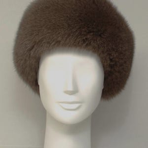 May include: A brown fur hat with a wide brim. The hat is made of soft, fluffy fur and has a simple, classic design.