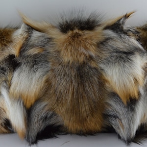 May include: Three decorative pillows made from fox fur. The pillows are a mix of gray, brown, and white fur.