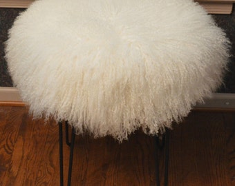 May include: White fluffy round ottoman with black hairpin legs.