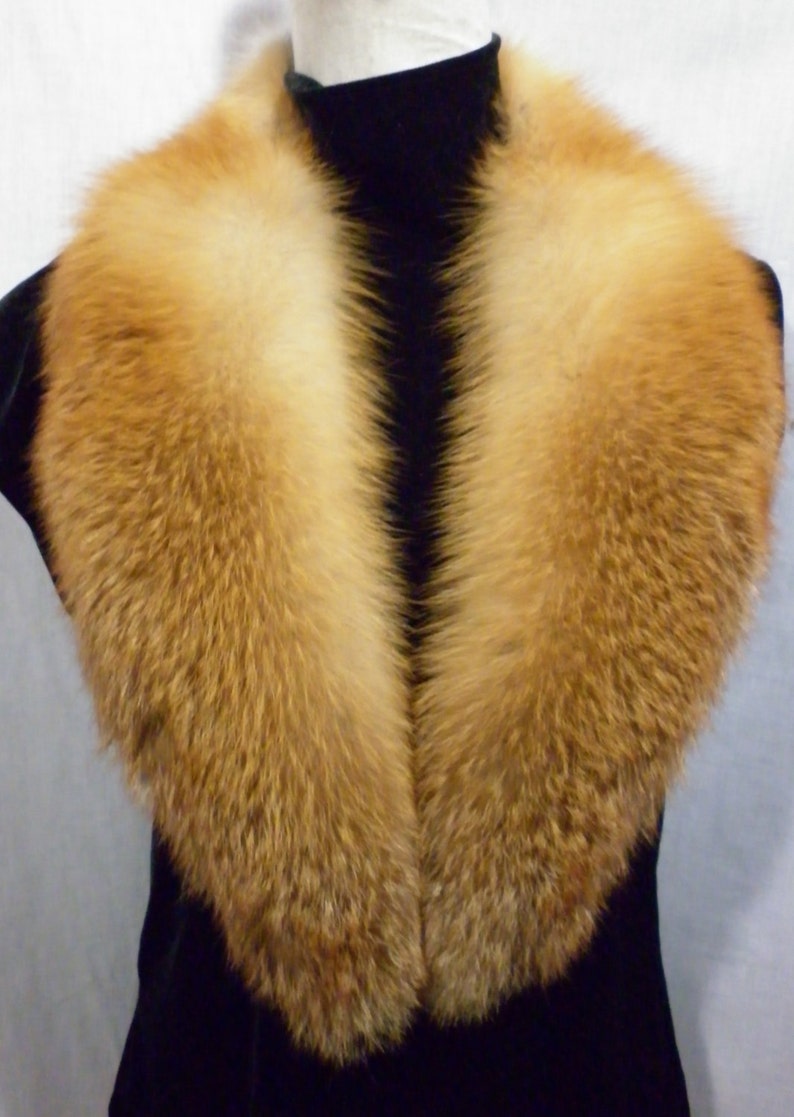May include: A large, fluffy fox fur collar in a rich orange color. The collar is made of real fur and has a soft, luxurious feel.