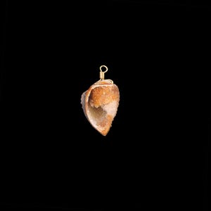 Peut inclure: Pendentif en forme de géode naturelle ouverte, avec un fil d'enroulement et une bélière dorés. La géode présente un extérieur rugueux et texturé dans des tons bruns et beiges, avec un intérieur cristallin et scintillant. Le fond est noir uni.