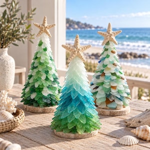 May include: Three cone-shaped decorative trees crafted from layered sea glass pieces in shades of green, blue, and white. Each tree is topped with a natural beige starfish and mounted on a circular wooden base, creating a coastal display.