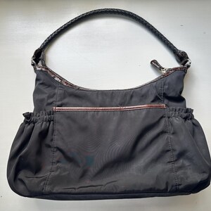 May include: A black nylon tote bag with a brown leather trim and a black leather handle.