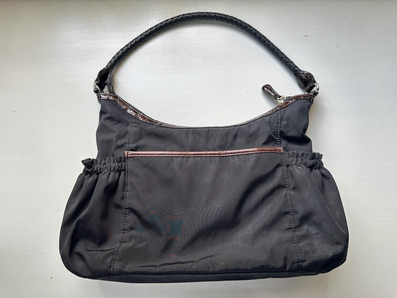 May include: A black nylon tote bag with a brown leather trim and a black leather handle.