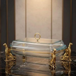 Fuente de cristal de lujo con tapa y base dorada con forma de animal. Elegante centro de mesa para una cena o evento especial.