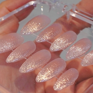 May include: A set of three ceramic mugs with a speckled, cream-colored glaze. Each mug features a different hand-painted design: a sun, a moon, and a star. The mugs have a simple, modern design with a rounded shape.