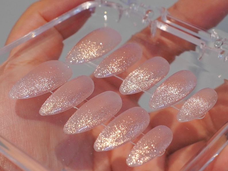 May include: A set of three ceramic mugs with a speckled, cream-colored glaze. Each mug features a different hand-painted design: a sun, a moon, and a star. The mugs have a simple, modern design with a rounded shape.