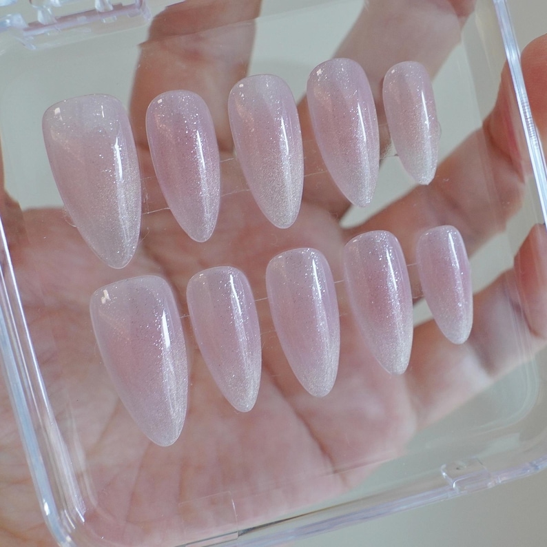 May include: A white ceramic mug with a black handle and the text "But First, Coffee" in a bold, black font. The mug is set against a blurred background, suggesting a cozy setting.