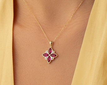 Op de afbeelding: Een gouden ketting met een hanger bestaande uit vier dieproze stenen in marquise-slijpvorm, gerangschikt in een bloemachtig patroon, geaccentueerd door kleine heldere ronde stenen gezet in goud tussen de bloemblaadjes aan een fijne schakelketting.