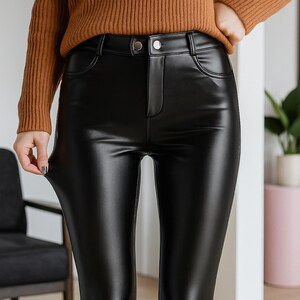 Puede incluir: Pantalones negros de cuero sint&eacute;tico con cintura alta y cierre de bot&oacute;n. Los pantalones tienen un acabado brillante y un dise&ntilde;o cl&aacute;sico de cinco bolsillos. La modelo lleva un su&eacute;ter marr&oacute;n.