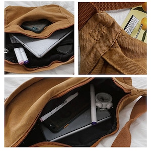 May include: A brown canvas messenger bag with a shoulder strap. The bag features multiple compartments, including a zipped main compartment and an external pocket. Inside, a tablet, phone, pens, and other items are visible. The bag is designed for carrying everyday essentials.