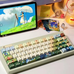 May include: A custom keyboard with keycaps featuring colorful illustrations. The keyboard has a light green frame and a variety of keycap colors, including white, beige, blue, and green. The text "KEYBOARD//KRAFT" is at the bottom.