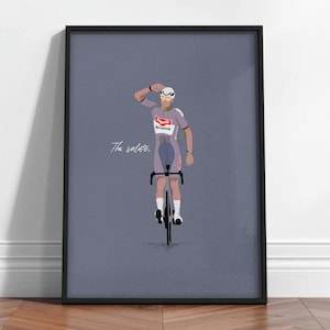 Puede incluir: Impresión enmarcada que presenta a un ciclista con uniforme gris y rojo, saludando. El ciclista está en una bicicleta negra sobre un fondo gris. El texto "The salute" está escrito en cursiva.