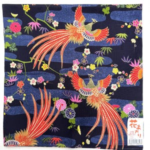 Op de afbeelding: Een marineblauw vierkant textiel met een Japans feniksontwerp. De feniksen hebben rode en oranje veren, tegen een achtergrond van gestileerde blauwe wolken en kleurrijke bloemaccenten. Het textiel is waarschijnlijk van katoen.