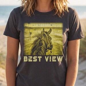 May include: A charcoal gray short-sleeve t-shirt featuring a square graphic print of a horse head in profile against a yellow-toned beach background. The text BEST VIEW is printed in a distressed, bold, light-colored font below the horse image.