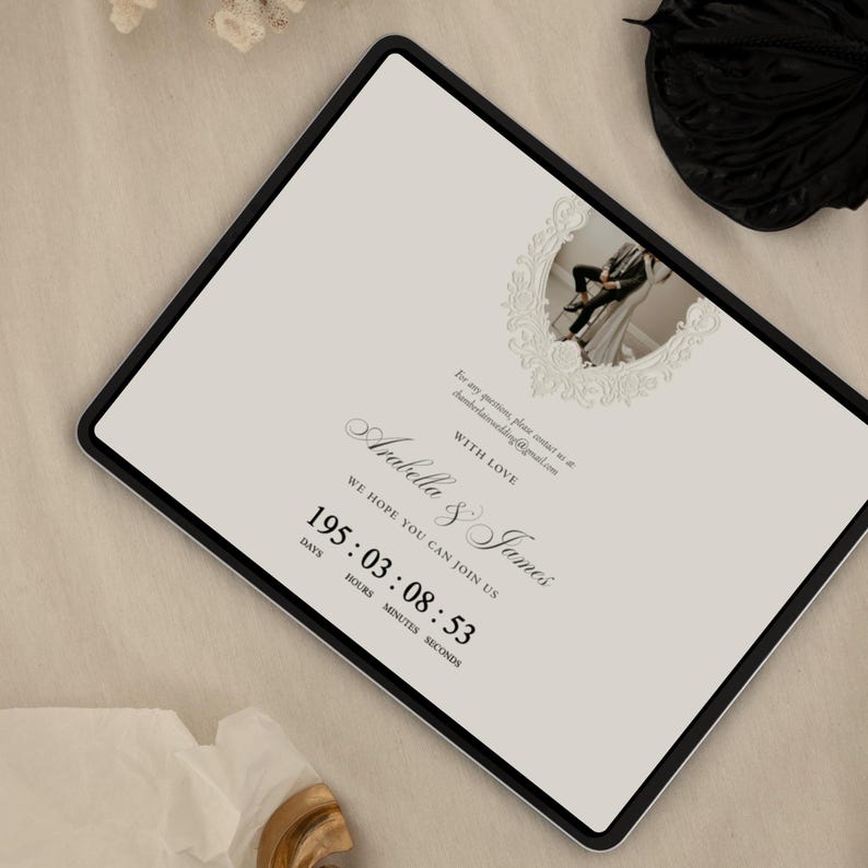 K&ouml;nnte beinhalten: Ein digitales Tablet mit einer Hochzeitseinladung auf cremefarbenem Hintergrund, einem kreisf&ouml;rmigen Foto eines Paares in einem dekorativen Rahmen, dem Text: With love, Arabella & James, we hope you can join us, und einem Countdown-Timer mit 195:03:08:53.