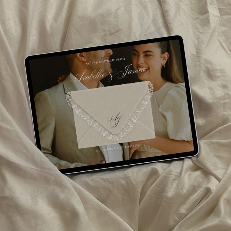 K&ouml;nnte beinhalten: Ein digitales Tablet zeigt einen Bildschirm mit einem cremefarbenen Umschlag mit Spitzenbesatz und dem Monogramm AJ. Der Text lautet YOU'VE GOT MAIL FROM Arabella & James und CLICK ENVELOPE TO OPEN. Der Hintergrund ist ein weicher wei&szlig;er Stoff.