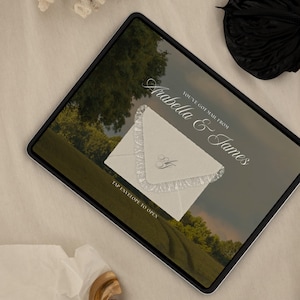 May include: A digital invitation on a tablet screen. The invitation features a cream-colored envelope with lace trim and the initials "A&J". Text reads "You've got mail from Arabella & James" and "Tap envelope to open".