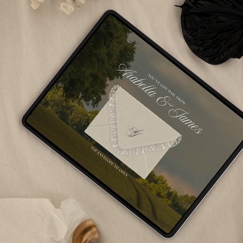 May include: A digital invitation on a tablet screen. The invitation features a cream-colored envelope with lace trim and the initials "A&J". Text reads "You've got mail from Arabella & James" and "Tap envelope to open".