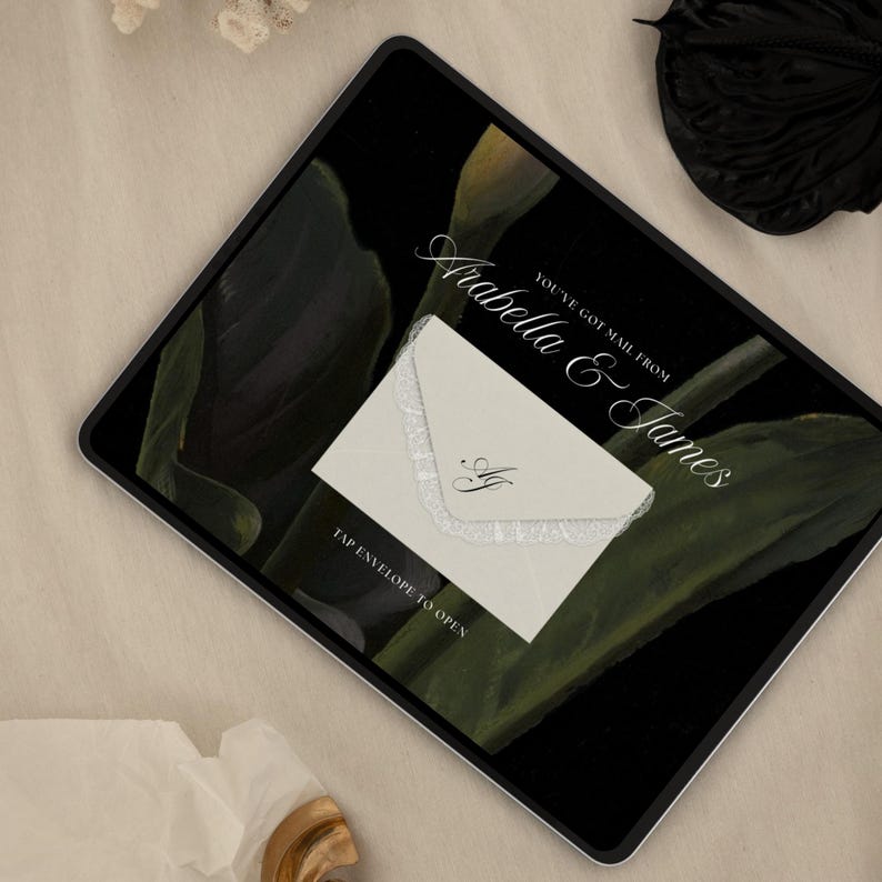 Puede incluir: Una invitaci&oacute;n digital en la pantalla de una tableta. El fondo presenta hojas de color verde oscuro. Un sobre blanco con ribete de encaje y las iniciales "AJ" est&aacute; centrado. El texto dice "Arabella & James" y "Tienes correo de." La parte inferior de la pantalla dice "Toca el sobre para abrir."