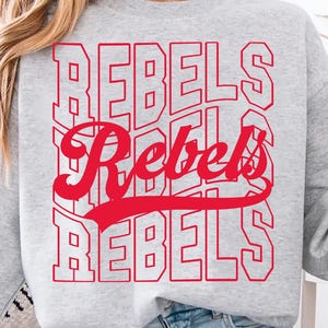 May include: A light gray sweatshirt with the word "REBELS" in red, stacked vertically and horizontally. The word "Rebels" is also written in a cursive font. A person is holding a green coffee mug.