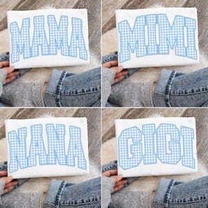 May include: Four white t-shirts, each with a different name in large, blue gingham letters: MAMA, MIMI, NANA, and GIGI. The shirts are displayed on a soft, light-colored surface.